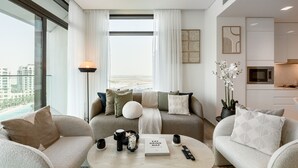 Ein modernes Wohnzimmer mit einer Sofagarnitur, einem Couchtisch und Blick auf die Stadtlandschaft.