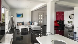 A modern living room with a white sofa, a coffee table, and a large window.