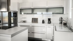 A modern kitchen with stainless steel appliances, white cabinetry, and a central island.