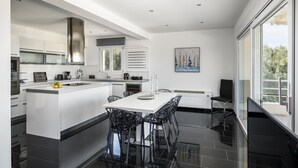 A modern kitchen with a central island, black chairs, and a dining table.