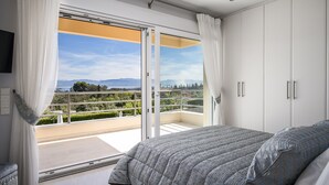 Ein Schlafzimmer mit einem großen Bett, einer Schiebetür zum Balkon und Blick auf die Landschaft.