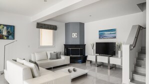 Ein modernes Wohnzimmer mit Sofa, Fernseher, Kamin und Kunstwerken an den Wänden.