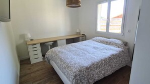 Un dormitorio con cama, escritorio y ventana.