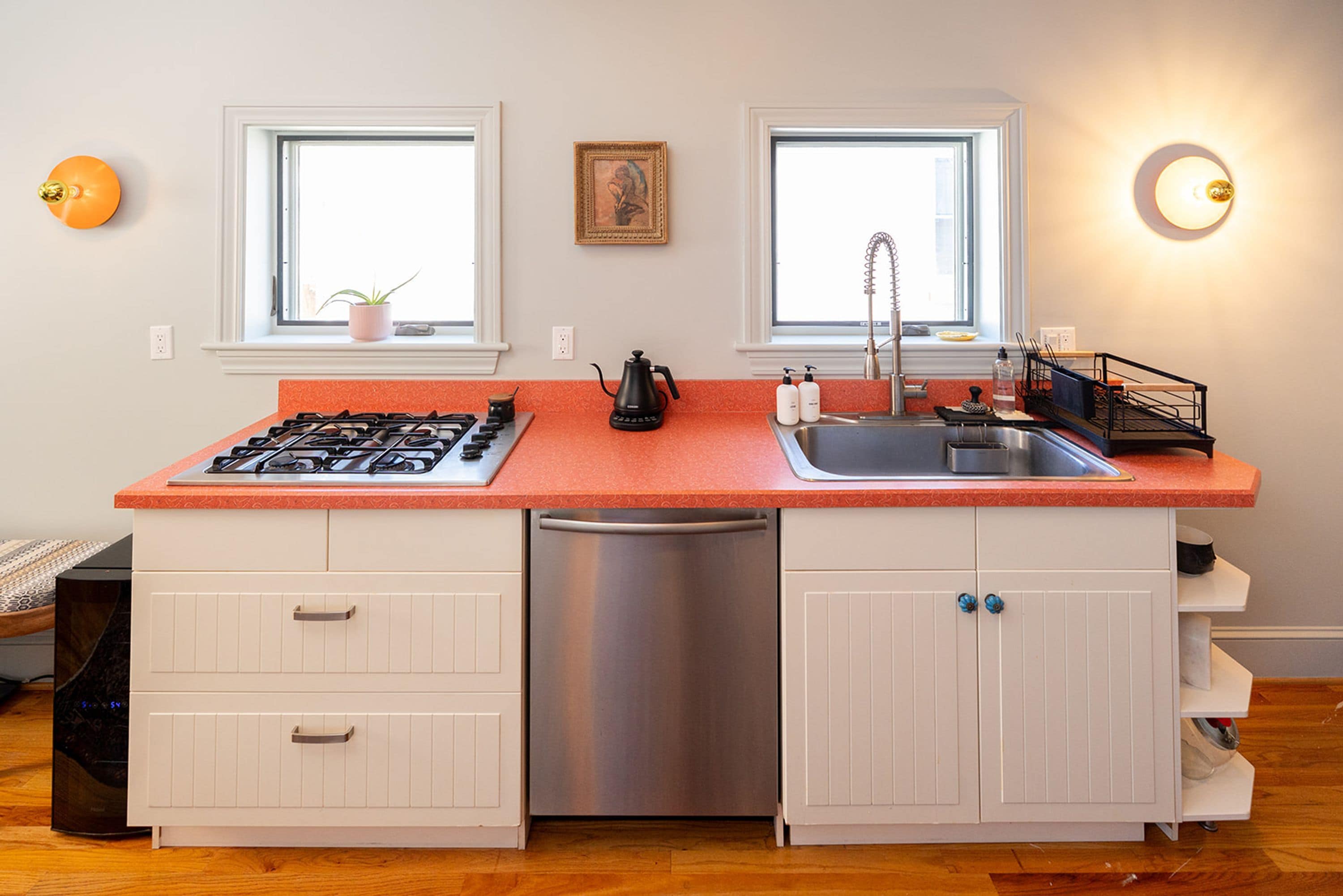 Cucina con piano cottura a gas, lavello e lavastoviglie, caratterizzata da mobili bianchi e un piano di lavoro rosso.