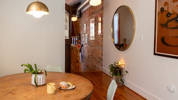 Un comedor con una mesa redonda de madera, una planta en maceta y un plato de comida.