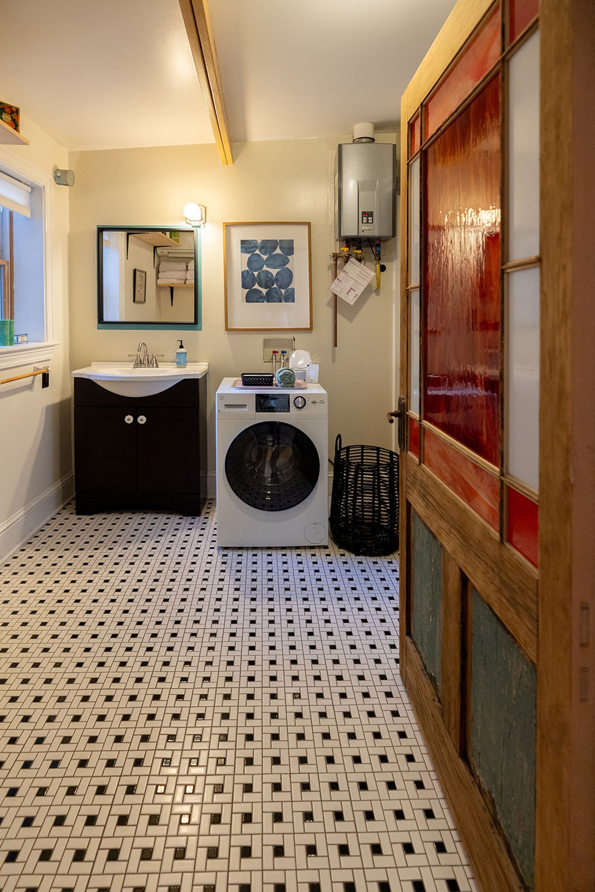 Un baño pequeño con lavadora, lavamanos y espejo.