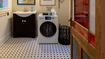 Un baño pequeño con lavadora, lavamanos y espejo.