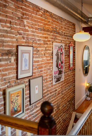 A brick wall with framed artwork and a mirror. - Wyatt's Saloon Guest House 2 (Baltimore)