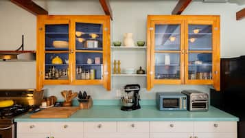 Una cocina con armarios de madera, una encimera, una estufa, una cafetera, un tostador y un microondas.
