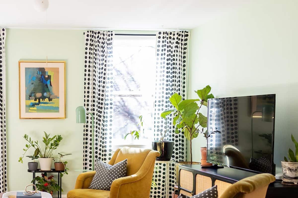 A living room with two yellow armchairs, a wooden coffee table, a television, and a patterned rug.