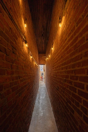 A narrow brick corridor with overhead lighting.