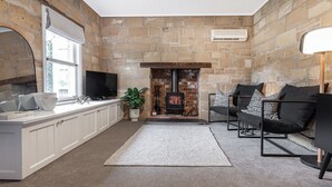 Una sala de estar acogedora con chimenea de piedra, armarios blancos y asientos cómodos.