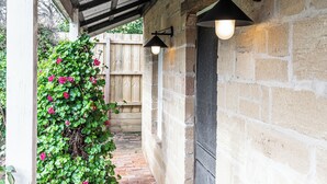Un espacio al aire libre cubierto con pared de ladrillo, valla de madera y plantas trepadoras.