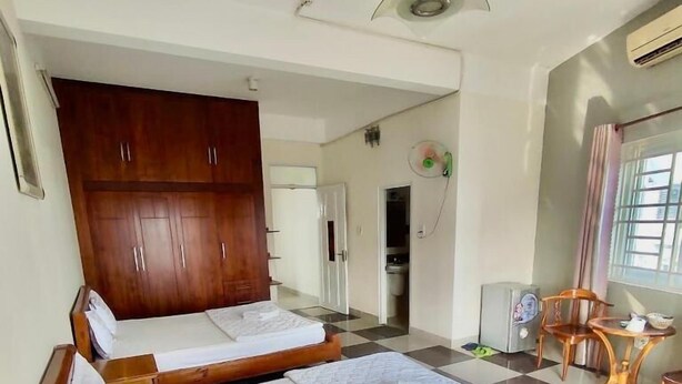 A hotel room with two beds, a wooden wardrobe, a small table, and a fan. - Hoang Nam Hotel Q2 SG- by Bay Luxury (Ho Chi Minh City)