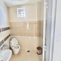Un baño con inodoro, lavamanos y zona de ducha.