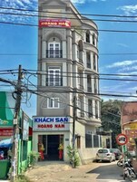 Un edificio de varios pisos con un letrero que dice "KHACH SAN HOANG NAM" y una fecha "HOAG 23/3/2017".