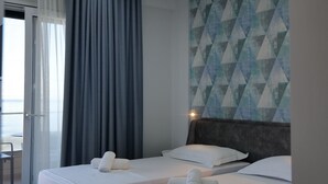 A hotel room with two beds, a balcony, and a geometric-patterned wall. - The Blue Wave Hotel (Himarë)