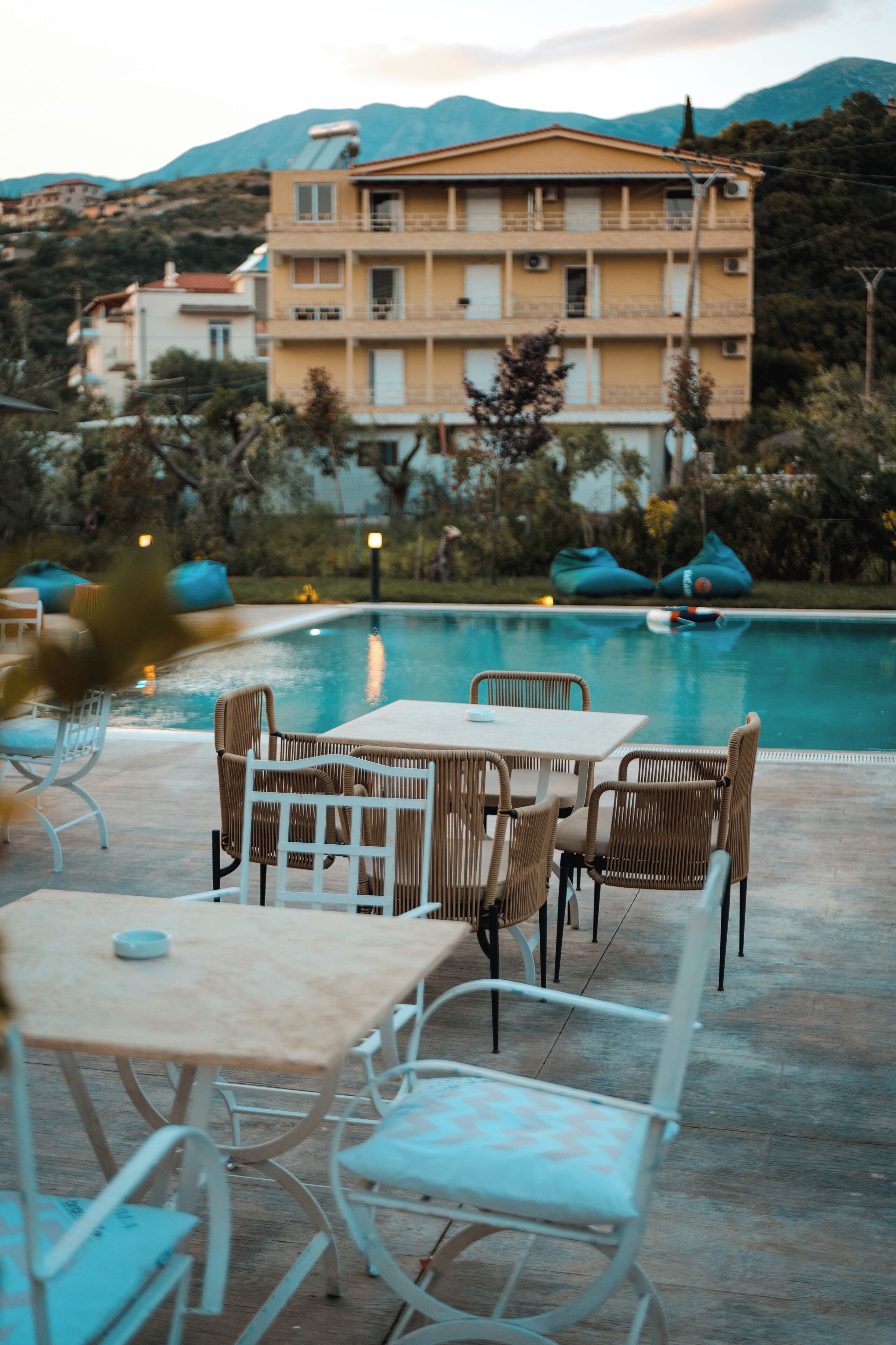 Zona junto a la piscina con mobiliario exterior y vista a un edificio al fondo.