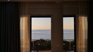A modern hotel room with a balcony overlooking the sea, a bed, a desk, and a chair. - The Blue Wave Hotel (Himarë)