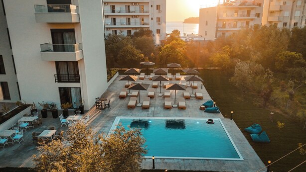 A rooftop pool area with lounge chairs and umbrellas, surrounded by apartment buildings. - The Blue Wave Hotel (Himarë)