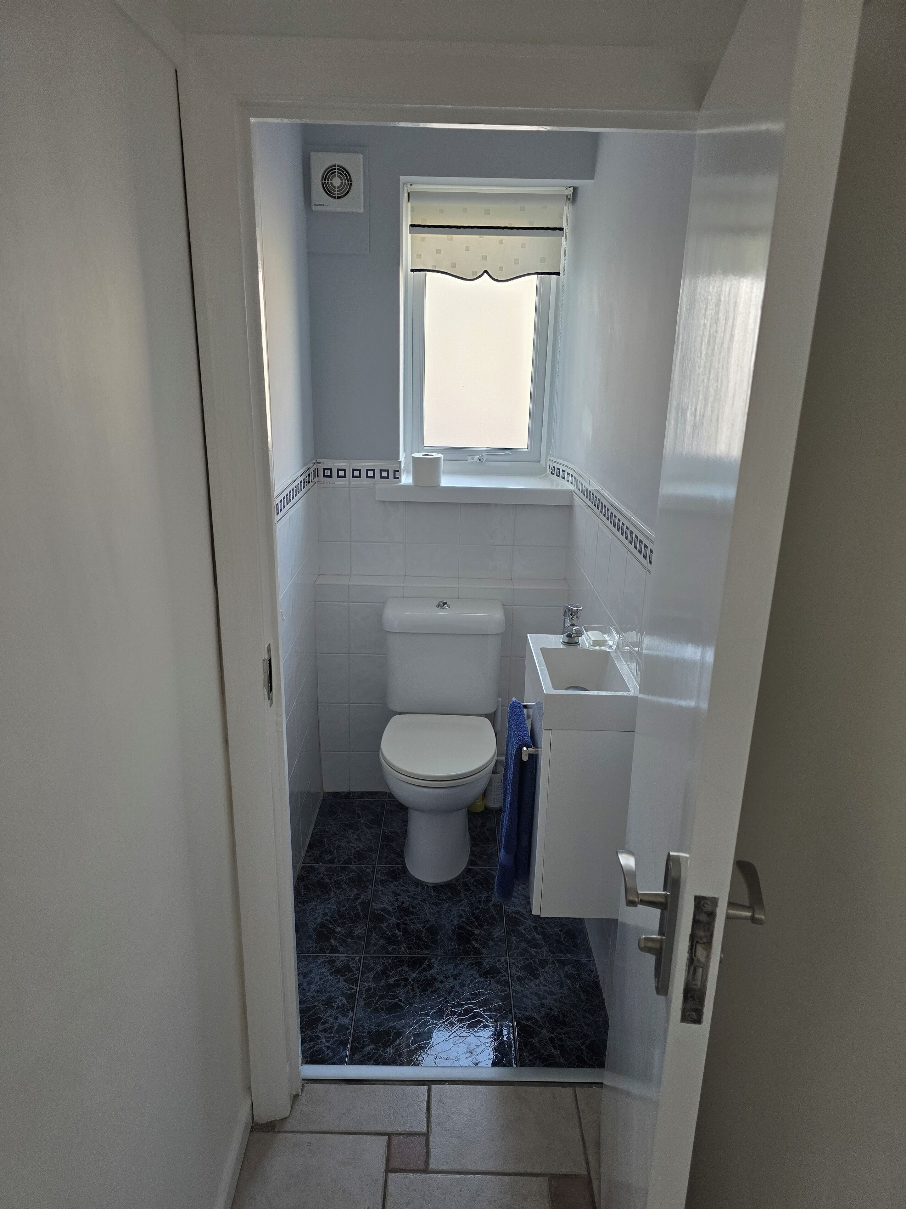 A small, compact bathroom with a toilet, a sink, and a window.