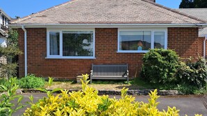 A two-story brick house with a tiled roof, a front porch, and a bench. - 2 bedroom chalet bungalow, short drive to The New Forest and Bournemouth beaches (Poole)