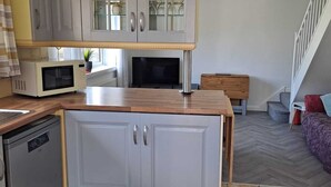 A compact kitchen with a microwave, dishwasher, and a wooden countertop. - 2 bedroom chalet bungalow, short drive to The New Forest and Bournemouth beaches (Poole)