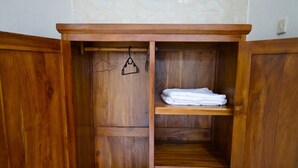 A wooden wardrobe with multiple shelves and hanging space. - Pondok Dete Guesthouse (Denpasar)