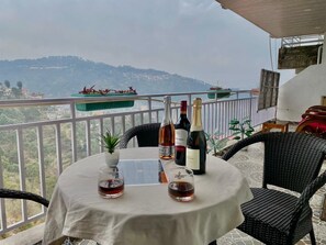 A balcony with a table set for two, featuring a bottle of wine, two glasses, and a menu. - Kasauli View (Solan)
