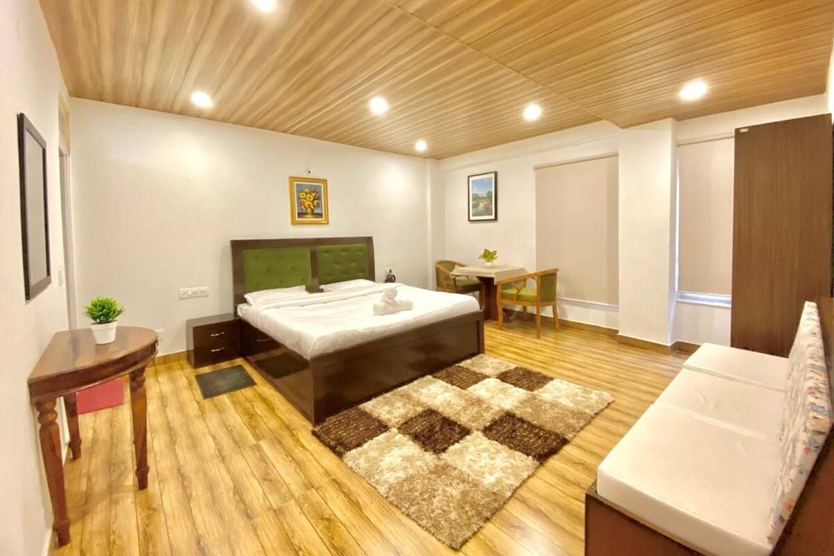 Ein Schlafzimmer mit Bett, Nachttisch, Stuhl und einem kleinen Tisch mit Pflanze.