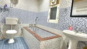 A bathroom with a bathtub, toilet, and sink, all tiled in blue and white. - Kasauli View (Solan)