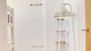 A room with a white wall, a wooden door, a white shelf unit, and a white ladder with shelves. - Apartamento El Mirador (Conil de la Fra.)