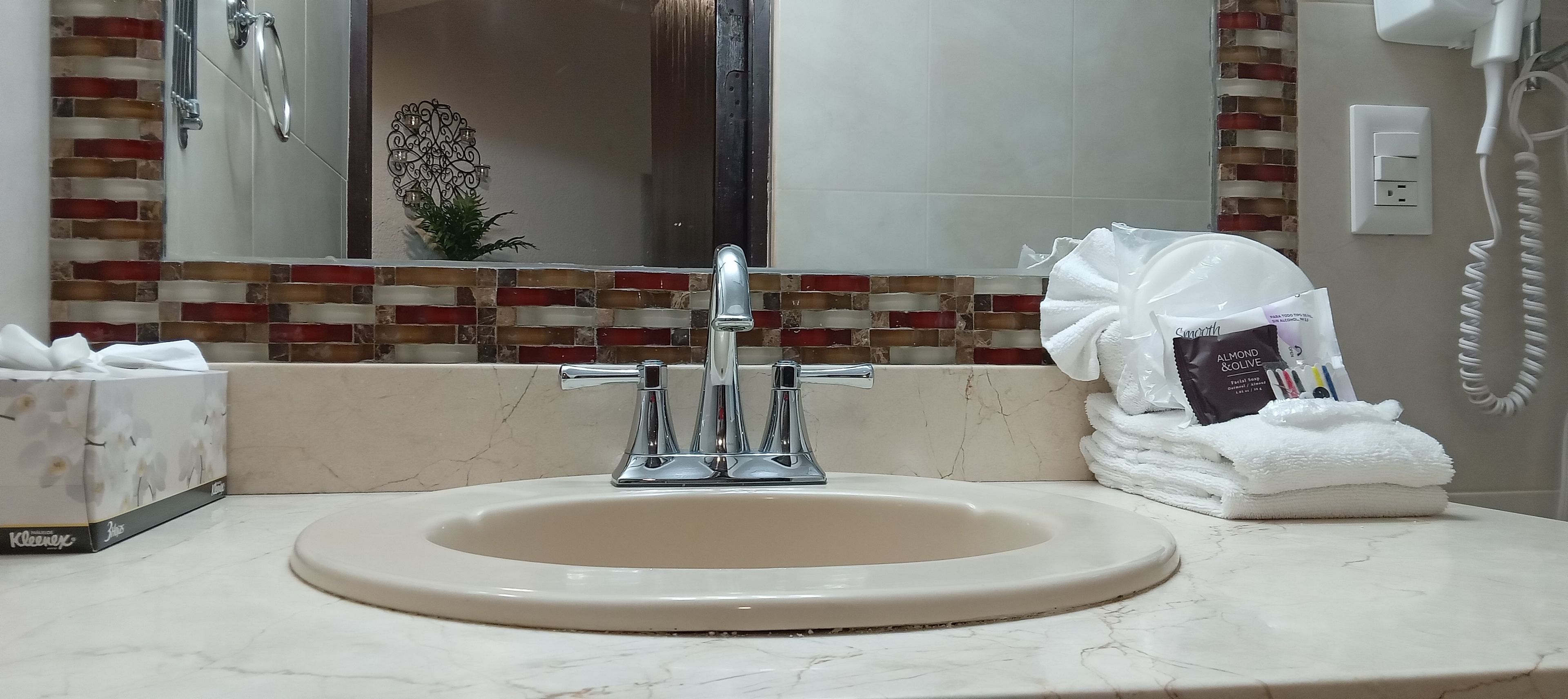 Un baño con lavamanos, espejo y una pila de toallas.