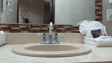 Un baño con lavamanos, espejo y una pila de toallas.
