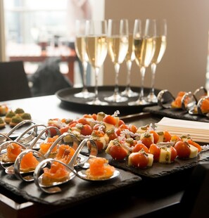 Una mesa con diferentes aperitivos y copas de vino blanco.