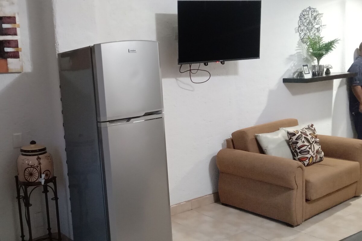 A kitchen with a refrigerator, a sink, and a tiled backsplash.