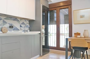 A modern kitchen with a geometric backsplash, a built-in oven, and a dining area with a wooden table and chairs.