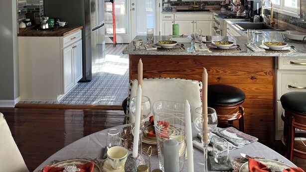 A spacious kitchen with wooden beams, a central island, and a dining area set for a meal. - “Lovely” Bungalow near downtown Quincy!  (Quincy)