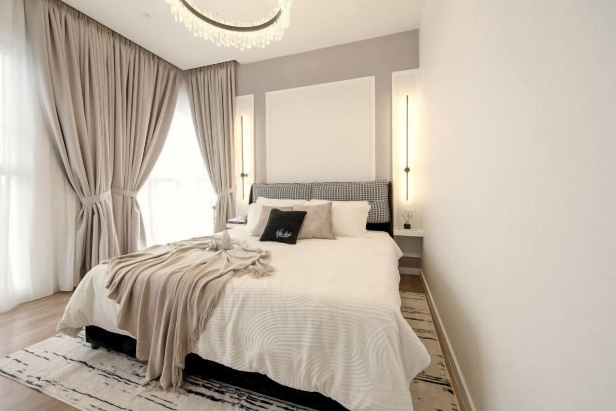 Ein modernes Schlafzimmer mit einem großen Bett, einer Pendelleuchte und Blick ins Freie.