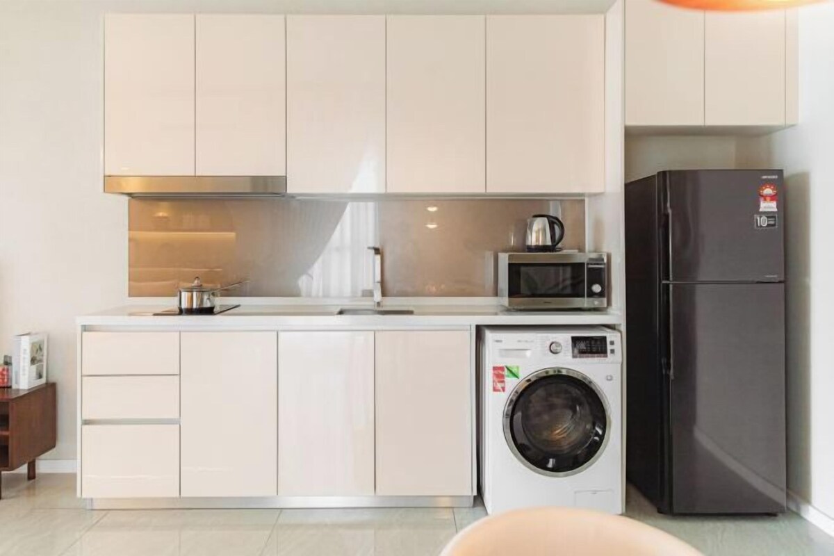 Eine kleine Küche mit Waschmaschine, Mikrowelle und Kühlschrank.