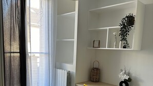 Ett sovrum med en säng, ett skrivbord med en stol, ett element och ett fönster med gardiner.