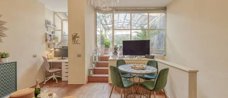 Un espacio habitable moderno con comedor, área de trabajo y un amplio ventanal con vista a zonas verdes.