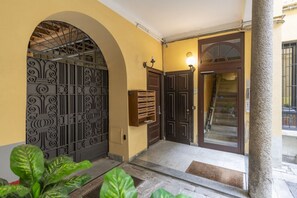 A building entrance with a metal gate, a wooden door, and a staircase leading inside.