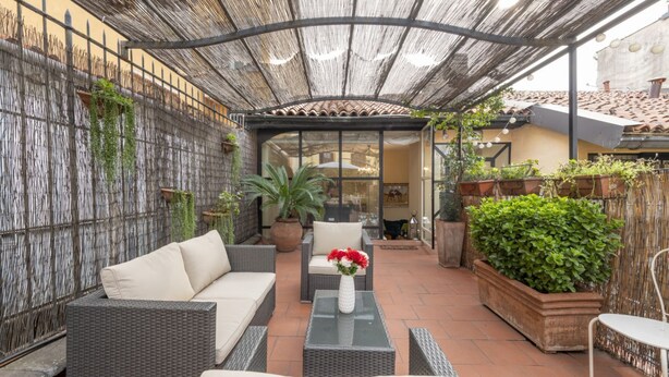 An outdoor patio with wicker furniture, a glass table, and potted plants. - BnButler - Pontaccio, 4 with terrace (Milano)