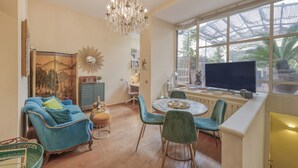A living room with a blue sofa, a chandelier, a round table, and a television. - BnButler - Pontaccio, 4 with terrace (Milano)