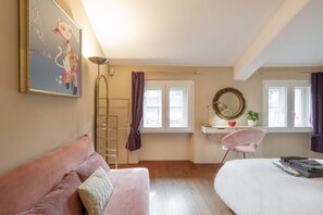 Un dormitorio con cama, escritorio, silla, escalera y un cuadro en la pared.