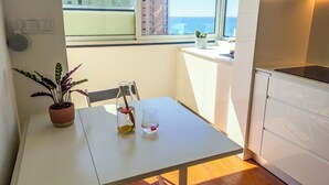 Une cuisine moderne avec vue sur la mer, une table à manger agrémentée d’une plante en pot et un verre contenant une boisson.