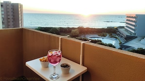 Un balcon avec une table, un verre et un bol d’olives.