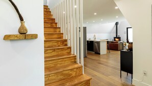 A modern interior with a wooden staircase, a kitchen area, and a fireplace. - Ridgeview A-Frame: Stylish Kerhonkson Escape (Kerhonkson)