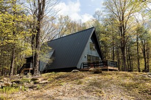 A modern cabin with a sloped roof, large windows, and a wooden deck. - Ridgeview A-Frame: Stylish Kerhonkson Escape (Kerhonkson)